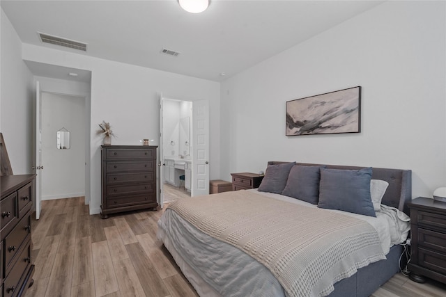 bedroom featuring ensuite bath and light hardwood / wood-style floors