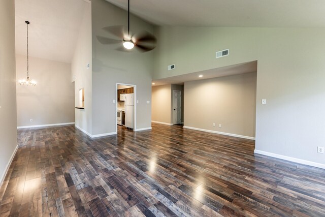 unfurnished living room with dark hardwood / wood-style flooring, ceiling fan with notable chandelier, and high vaulted ceiling