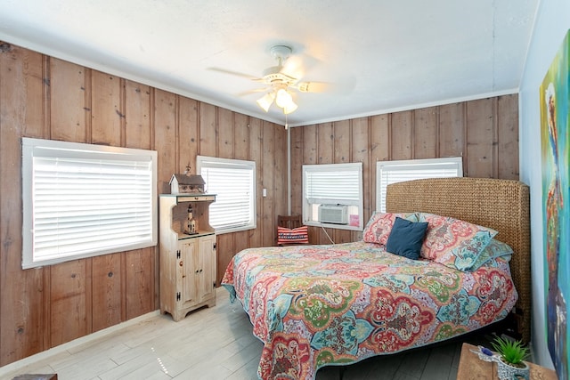 bedroom with wood walls, ceiling fan, light hardwood / wood-style floors, and cooling unit