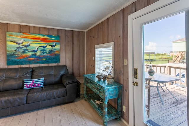 living room with wood walls, light hardwood / wood-style floors, and a textured ceiling