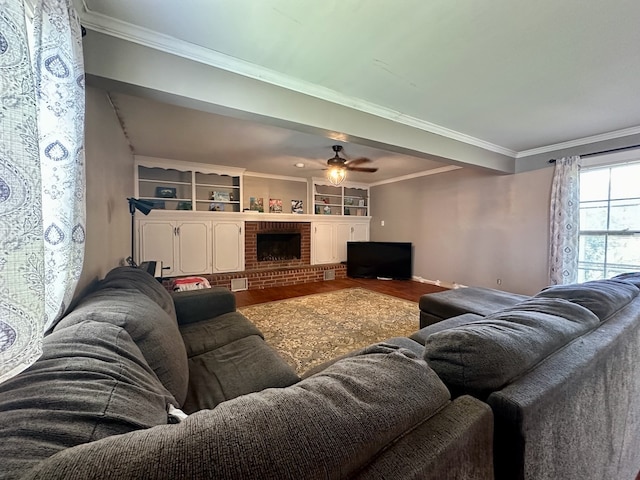 living room with built in features, ceiling fan, a fireplace, and crown molding