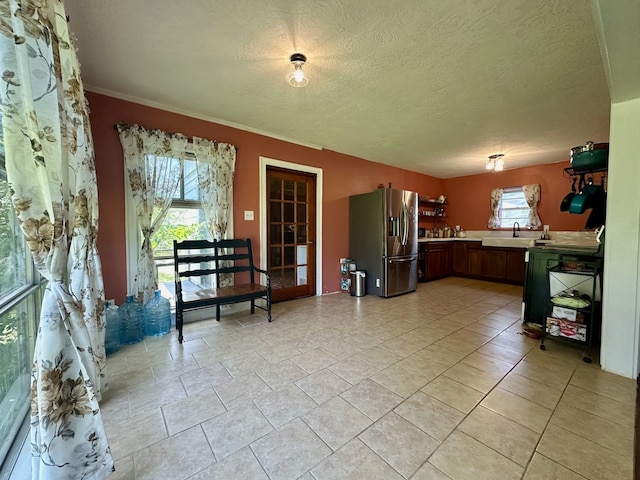 kitchen featuring sink, stainless steel fridge, a textured ceiling, and light tile floors