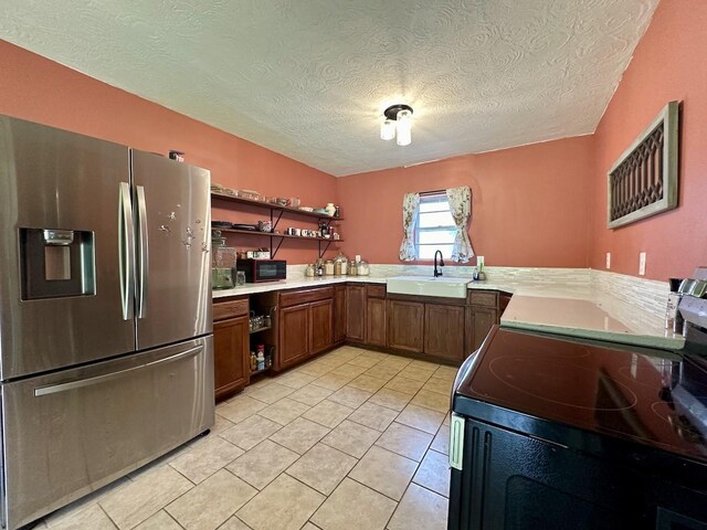 kitchen with stainless steel refrigerator with ice dispenser, a textured ceiling, range, light tile floors, and sink