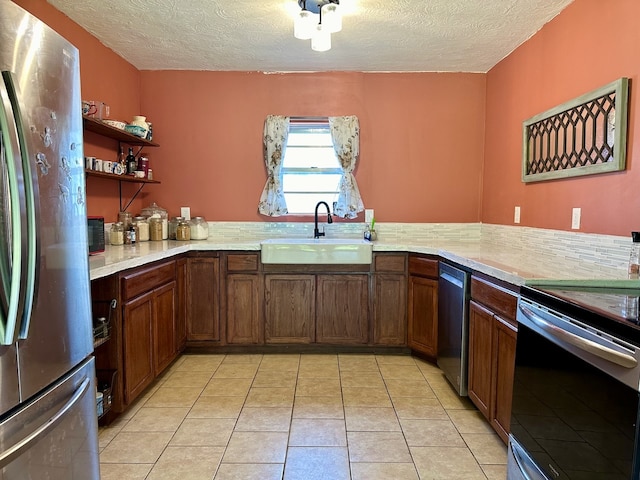 kitchen with sink, a textured ceiling, light tile floors, and appliances with stainless steel finishes