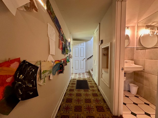 corridor featuring tile flooring, sink, and tile walls