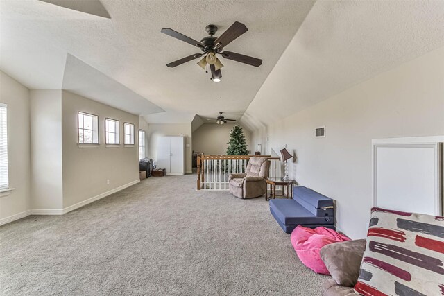 interior space featuring a textured ceiling, carpet, ceiling fan, and vaulted ceiling