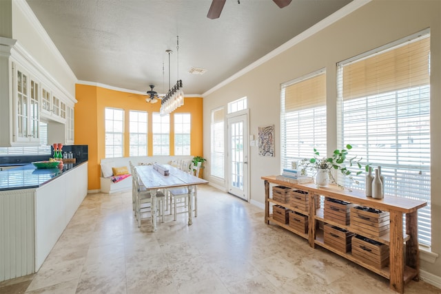 tiled dining area with ceiling fan and crown molding