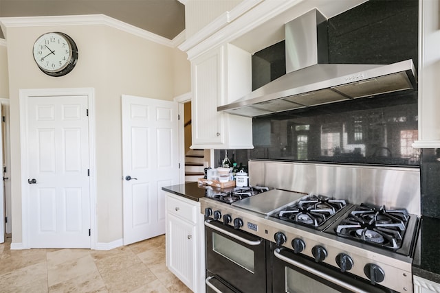 kitchen with double oven range, white cabinetry, tasteful backsplash, and wall chimney exhaust hood