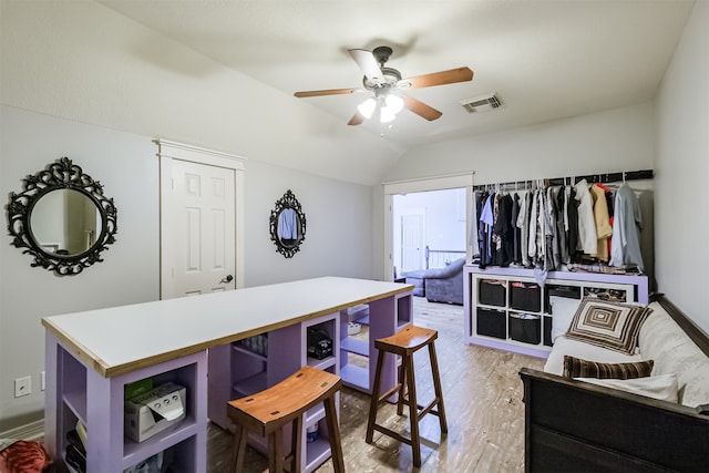 kitchen with a kitchen island, vaulted ceiling, ceiling fan, and light hardwood / wood-style flooring