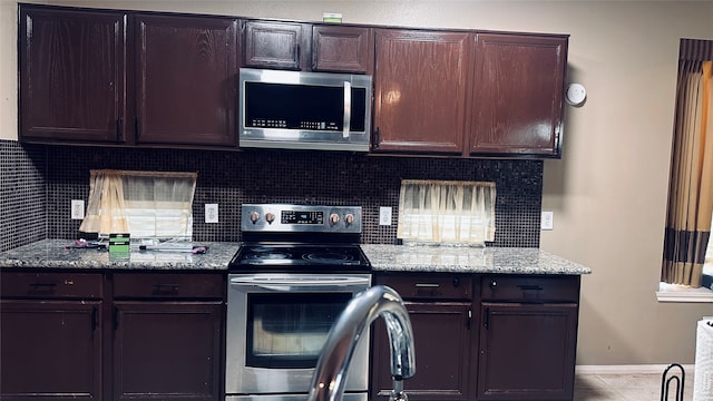 kitchen with backsplash, dark brown cabinetry, appliances with stainless steel finishes, and light stone counters