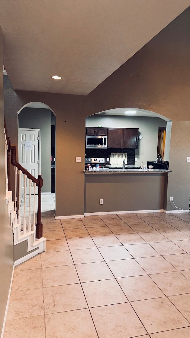 kitchen featuring dark brown cabinetry, stainless steel appliances, tasteful backsplash, and light tile flooring