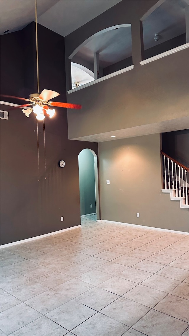 unfurnished room with a towering ceiling, ceiling fan, and tile floors