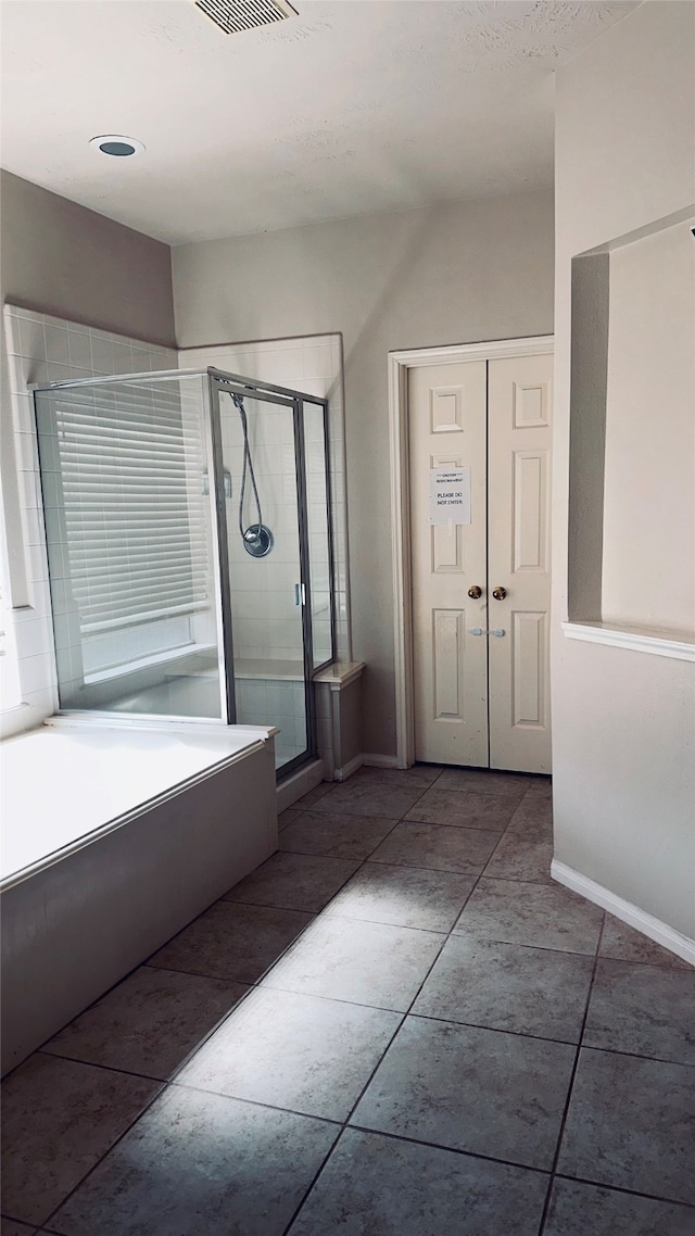 bathroom with a shower with shower door and tile flooring