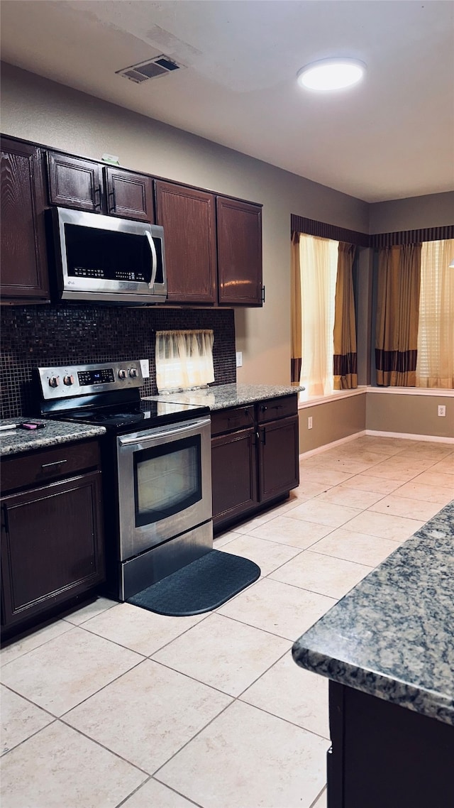 kitchen featuring appliances with stainless steel finishes, dark brown cabinets, tasteful backsplash, and light tile floors