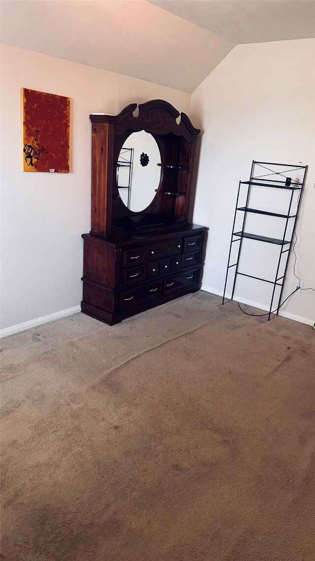 unfurnished bedroom with vaulted ceiling and carpet