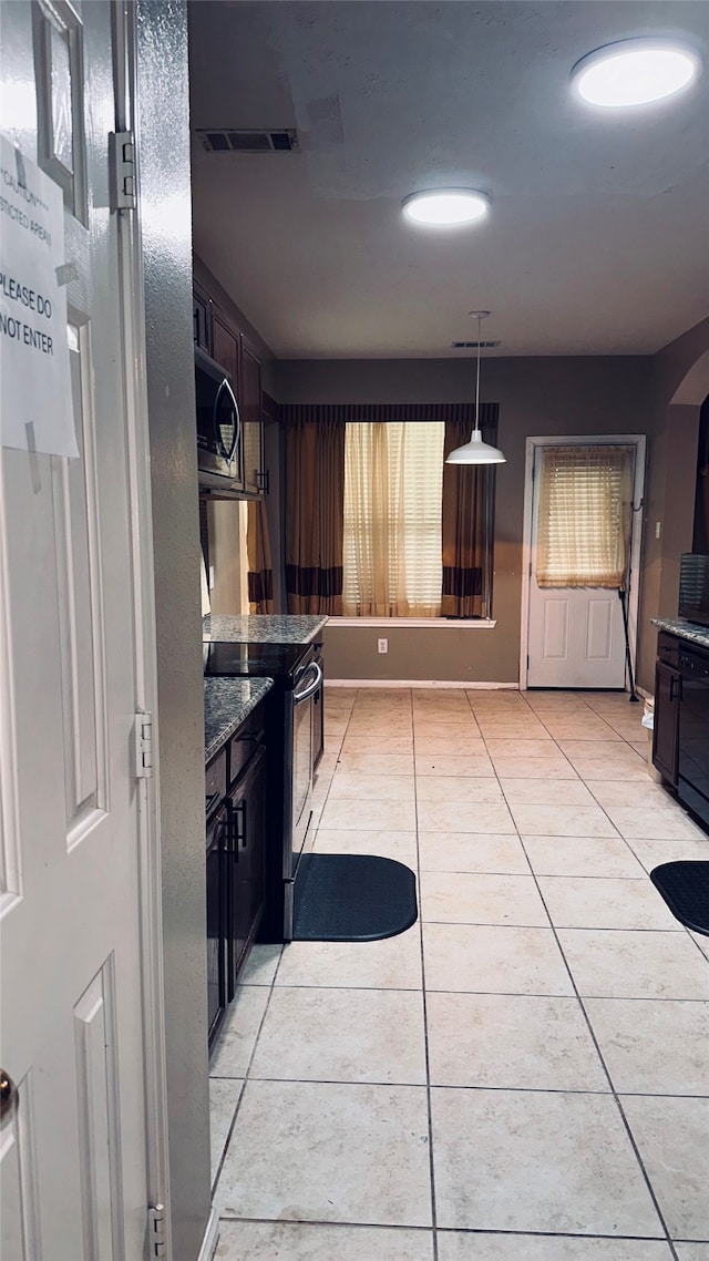 kitchen with dark stone counters, dark brown cabinets, electric stove, decorative light fixtures, and light tile floors