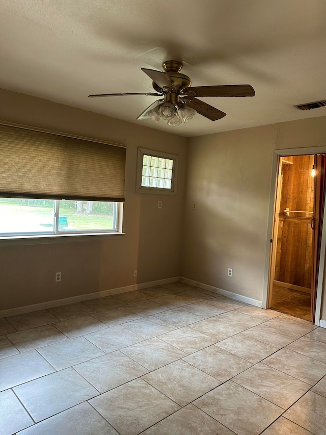 tiled spare room featuring ceiling fan