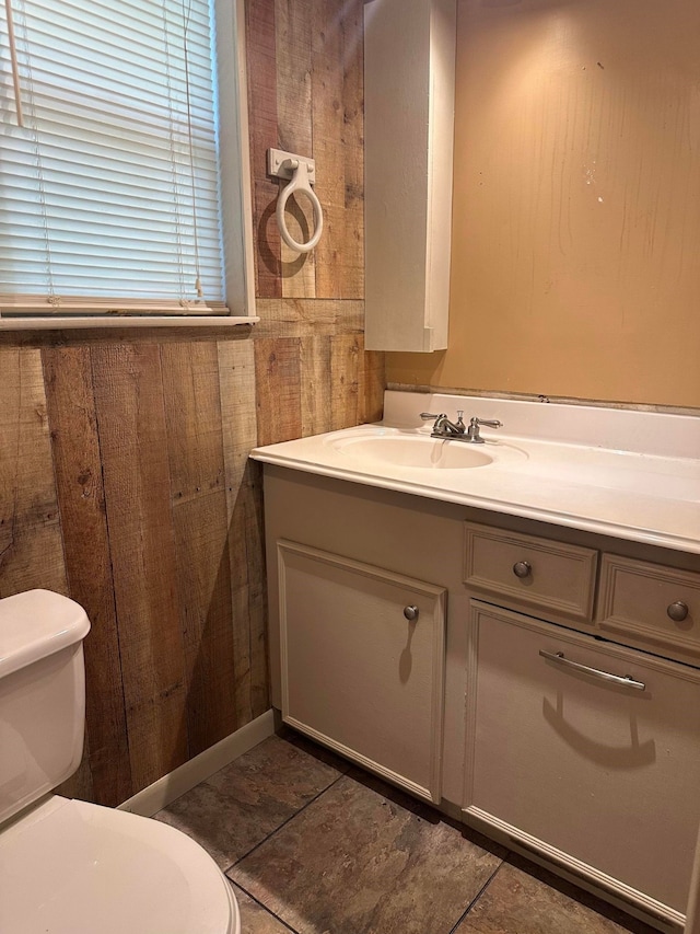 bathroom with wood walls, tile patterned flooring, vanity, and toilet