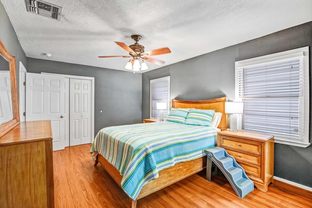 bedroom featuring a textured ceiling, ceiling fan, a closet, and light hardwood / wood-style floors