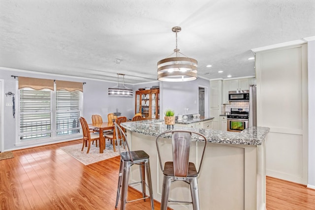 kitchen featuring light stone countertops, pendant lighting, a center island, stainless steel appliances, and tasteful backsplash