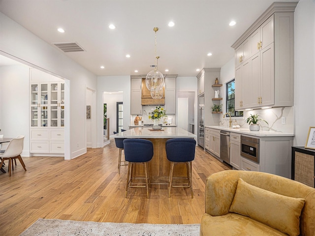 kitchen featuring built in appliances, a kitchen island, gray cabinets, and hanging light fixtures