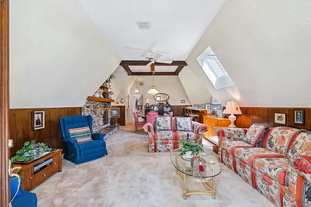 carpeted living room featuring a textured ceiling, a fireplace, wood walls, lofted ceiling with skylight, and ceiling fan