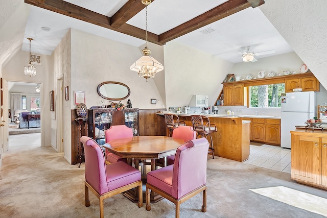 dining space with beamed ceiling, ceiling fan with notable chandelier, light carpet, and high vaulted ceiling