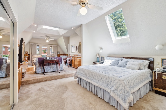 carpeted bedroom featuring ceiling fan, vaulted ceiling with skylight, and a textured ceiling