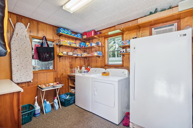 washroom featuring carpet flooring, wood walls, a wall unit AC, and washing machine and clothes dryer