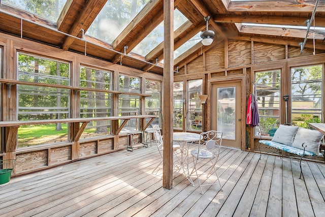 unfurnished sunroom featuring ceiling fan, a wealth of natural light, lofted ceiling with skylight, and wooden ceiling