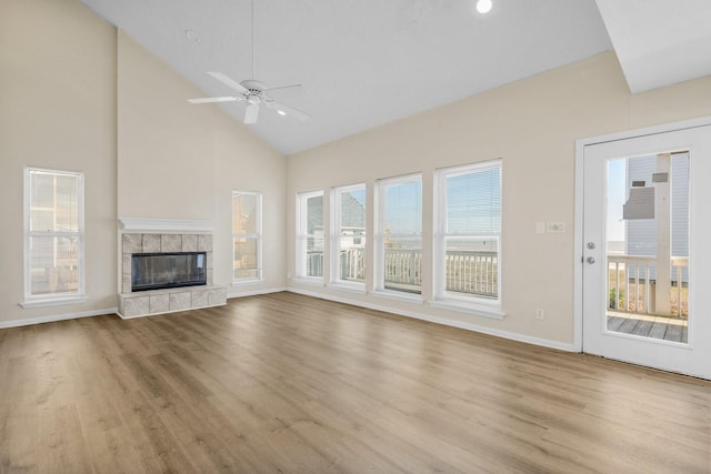 unfurnished living room with a tile fireplace, light wood-type flooring, high vaulted ceiling, and ceiling fan