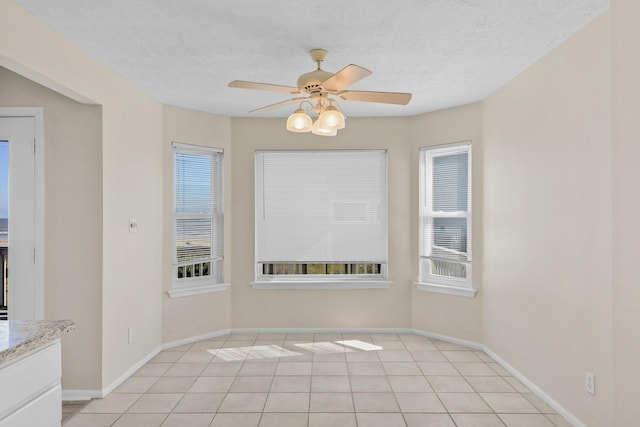 unfurnished room featuring light tile patterned flooring, a wealth of natural light, ceiling fan, and a textured ceiling