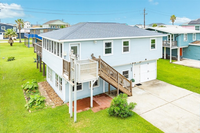 back of house with a garage, concrete driveway, roof with shingles, and a lawn