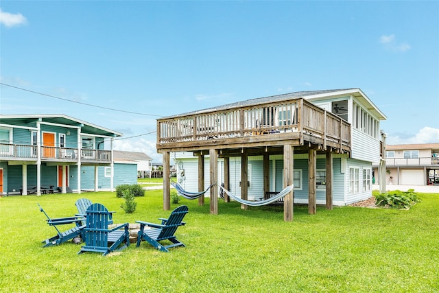 back of house with a garage, an outdoor fire pit, a deck, and a lawn