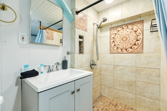 full bathroom featuring tiled shower and vanity