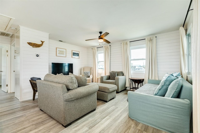 living room featuring ceiling fan, light wood-type flooring, visible vents, and attic access