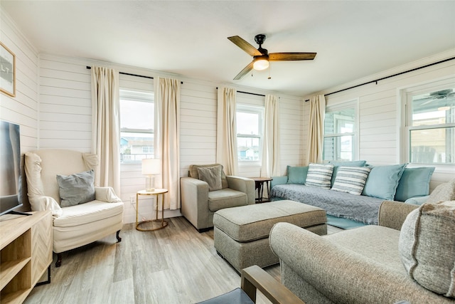 living room featuring ceiling fan, wooden walls, and wood finished floors