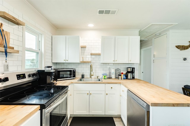 kitchen with visible vents, wood counters, a peninsula, stainless steel appliances, and open shelves