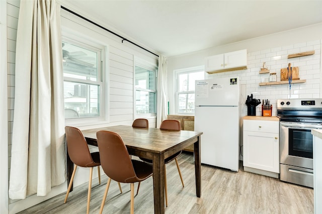 kitchen featuring freestanding refrigerator, white cabinetry, light wood finished floors, and stainless steel electric stove