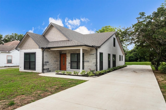 129 S Grace St, Crockett, TX 75835 - view of front facade with stone siding, a front yard, and roof with shingles