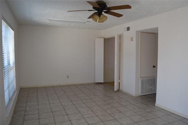 tiled empty room featuring ceiling fan and a textured ceiling