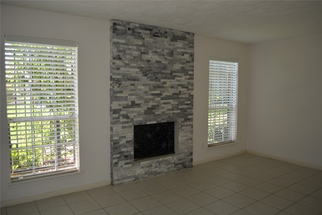 unfurnished living room featuring light tile patterned floors, a fireplace, and a wealth of natural light