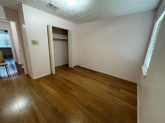 unfurnished bedroom featuring hardwood / wood-style flooring, a textured ceiling, and a closet