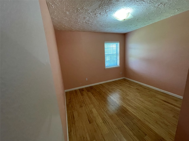 unfurnished room with wood-type flooring and a textured ceiling