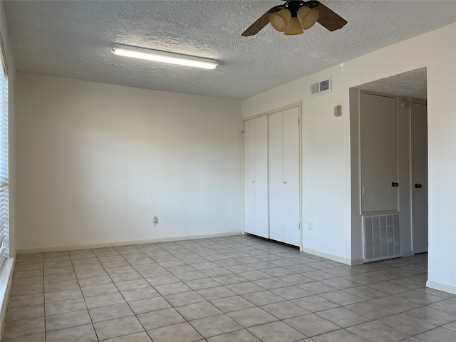 tiled empty room featuring ceiling fan and a textured ceiling