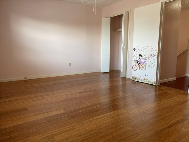 empty room with dark hardwood / wood-style floors and a textured ceiling