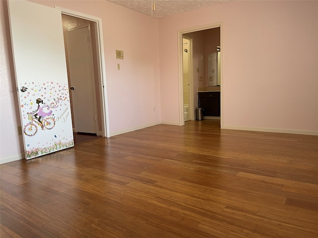 spare room featuring dark hardwood / wood-style floors and a textured ceiling