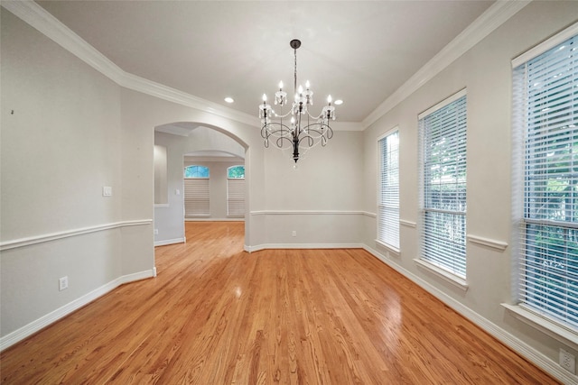 unfurnished dining area featuring light wood-type flooring, crown molding, and a notable chandelier