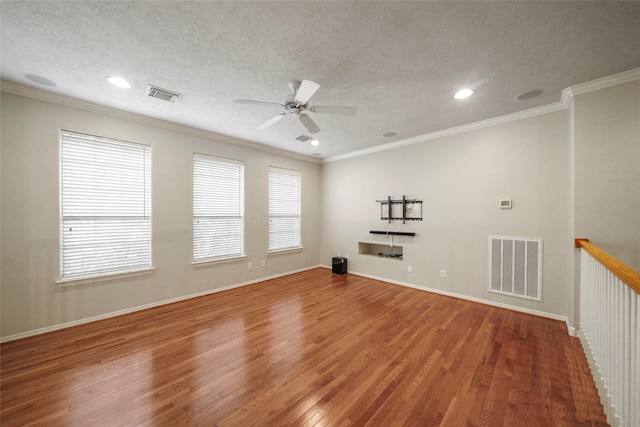 unfurnished room with hardwood / wood-style floors, a textured ceiling, a wealth of natural light, and crown molding