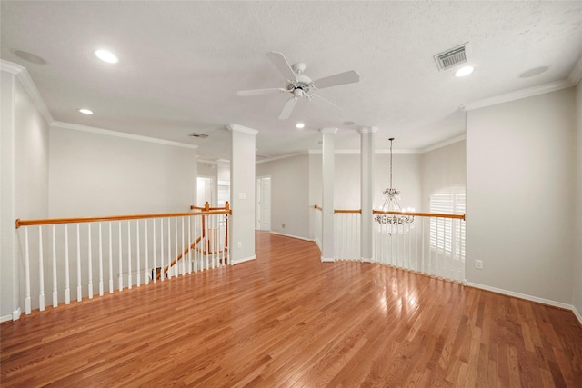 empty room featuring hardwood / wood-style flooring, ceiling fan with notable chandelier, crown molding, and a textured ceiling